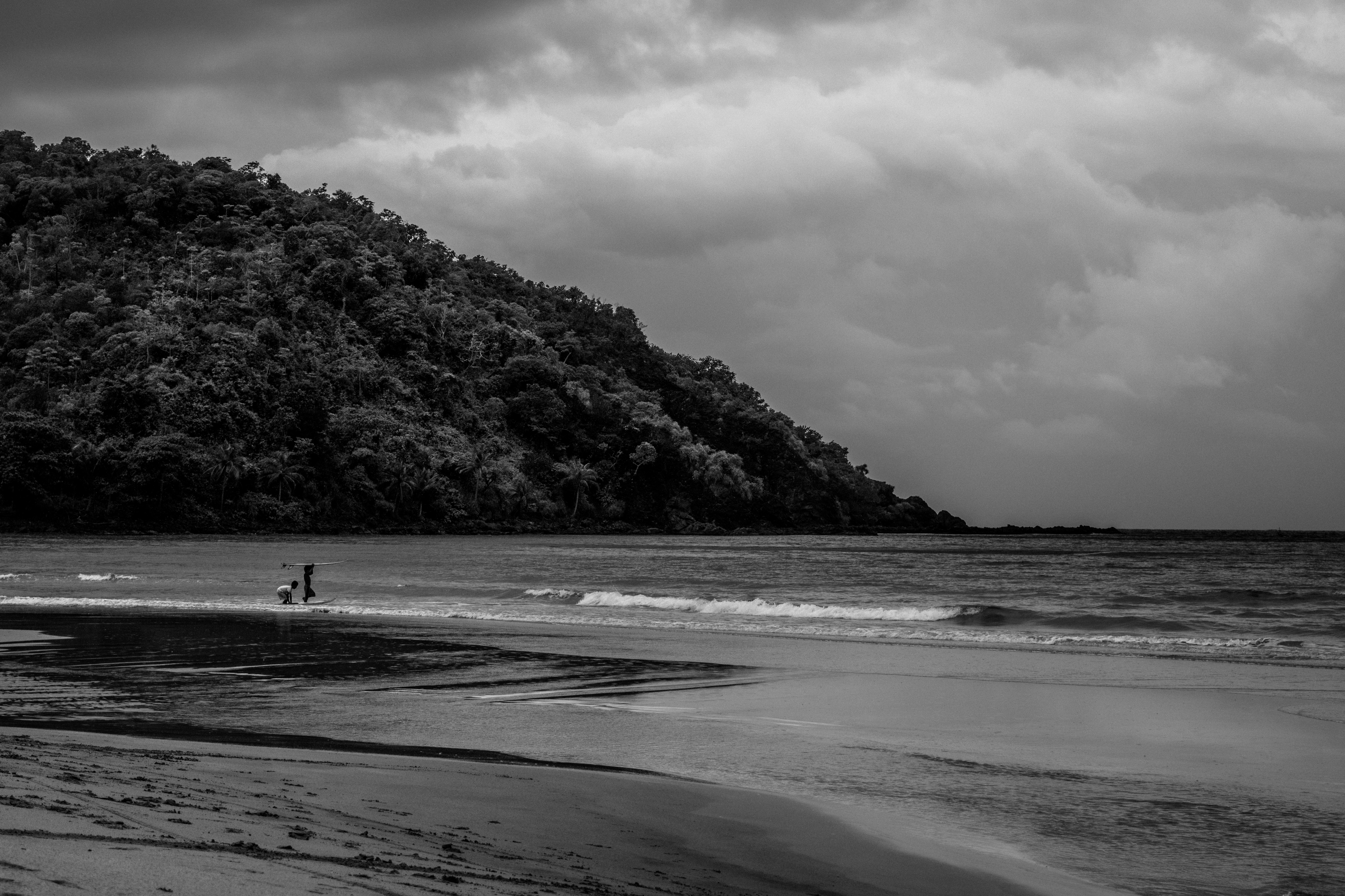 grayscale photo of 2 people walking on beach